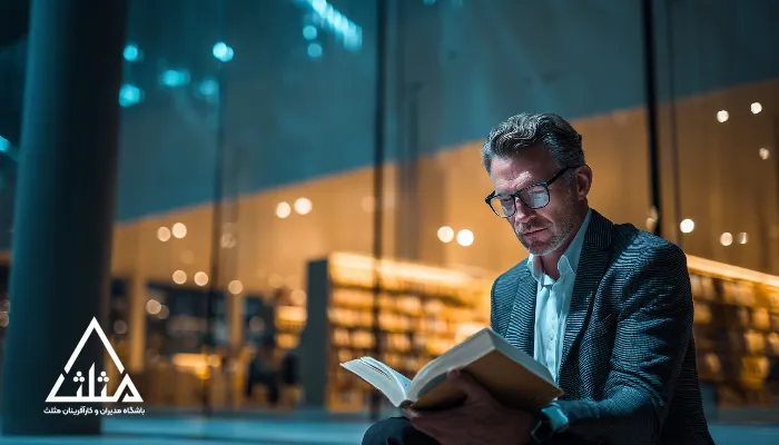 تصویر یک مدیر در حال مطالعه در فضای کتابخانه مدرن؛ نمادی از اهمیت دانش برای مدیران و کارآفرینان در رشد، تصمیم‌گیری و توسعه کسب‌وکار