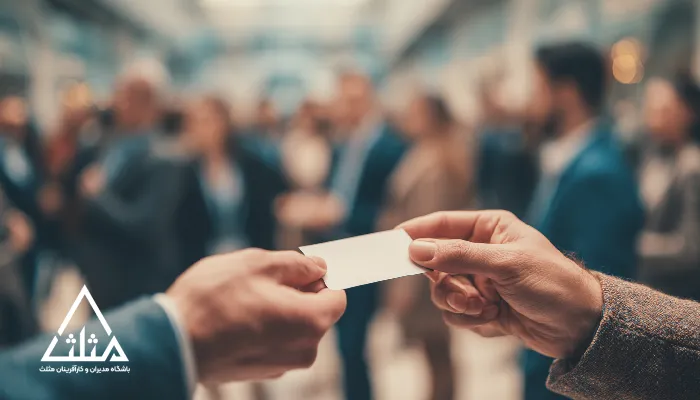 تصویر تبادل کارت ویزیت میان افراد در یک رویداد حرفه‌ای؛ نمادی از اهمیت شبکه‌سازی برای کسب‌وکارها در ایجاد ارتباطات مؤثر، فرصت‌های همکاری و رشد تجاری.
