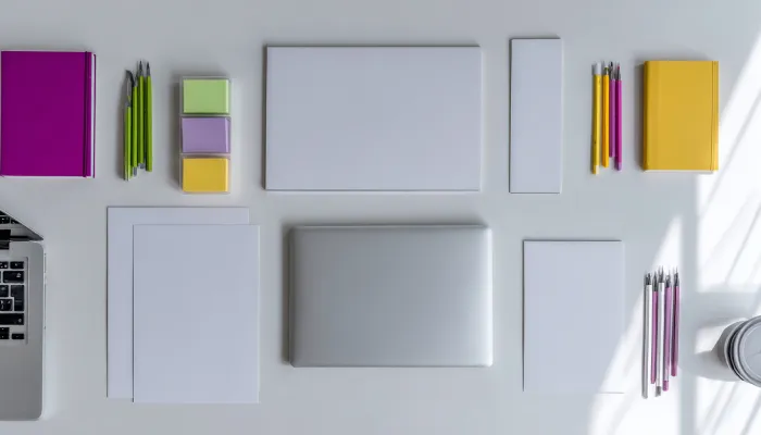 چیدمان مینیمال و رنگی از ابزارهای اداری و تحریری روی میز سفید، نمادی از نظم، دقت و فرآیند تولید محتوا در تحریریه وب‌سایت باشگاه مدیران و کارآفرینان مثلث.