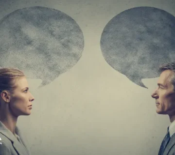 گفت‌وگوی رودررو میان یک زن و یک مرد با حباب‌های گفتار روبه‌روی هم، نماد ارتباط مؤثر، تفاهم متقابل و مهارت‌های ارتباطی در مذاکره و تعامل انسانی